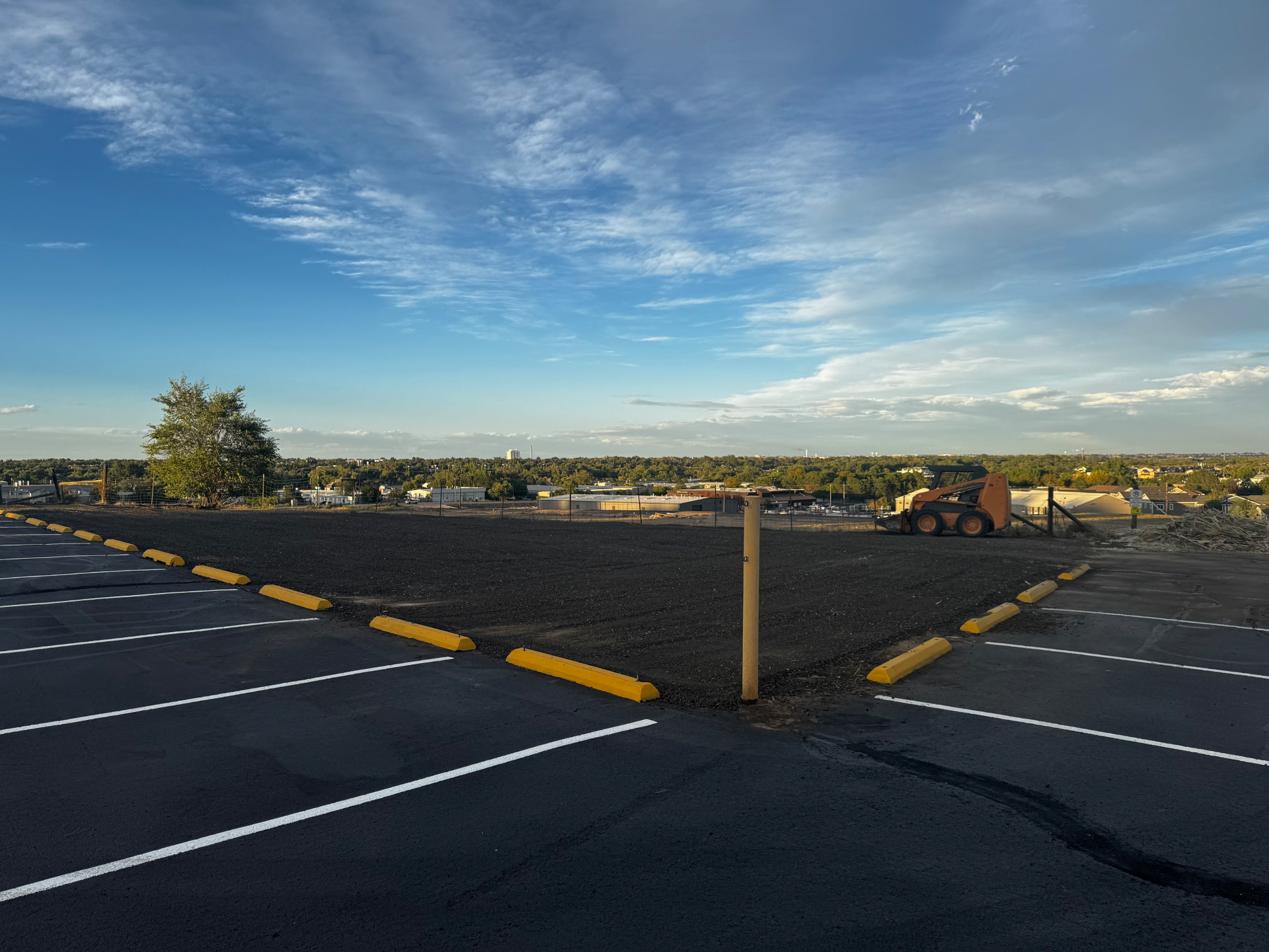 Freshly sealcoated commercial parking lot with new striping and yellow wheel stops